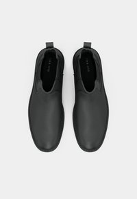 Pantofi negri tip slip-on, din piele netedă, cu panouri elastice pe laturi și o bandă de prindere în spate. Vârf rotunjit și detalii minime de coasere.