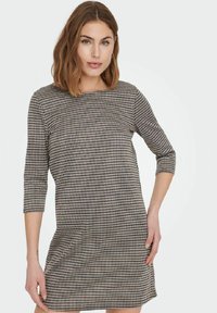 Svart och vit klänning i houndstooth-mönster med trekvartslånga ärmar, rund halsringning och avslappnad passform, gjord av ett texturerat tyg.