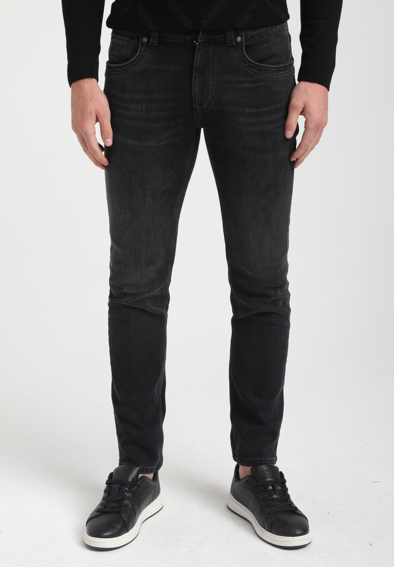 Mustad venitam denim püksid kitsa lõikega, viie taskuga ja keskmise kõrgusega vöökoht. Kombineeritud mustade spordijalatsitega.