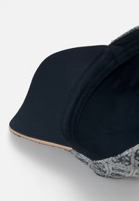 Casquette avec une doublure intérieure bleu marine foncé et un extérieur gris à motifs. La visière est courbée, avec une finition lisse et des détails de surpiqûres subtils.
