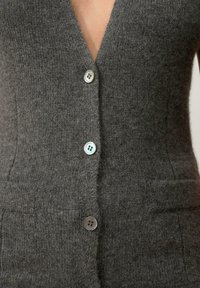 Cardigan de lana gris con un profundo escote en V, seis botones en la parte delantera y dos bolsillos laterales, con una textura suave y un diseño ajustado.