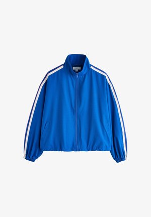 Blå trackjakke med lynlås, hvide og røde striber langs ærmerne, elastiske manchetter og sidelommer.