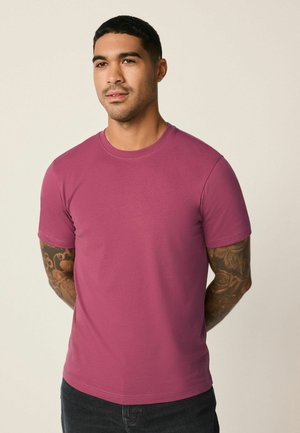 Kurzärmeliges Rundhals-T-Shirt in tiefem Magenta, aus einer weichen Baumwollmischung mit glatter Textur und figurbetonter Silhouette.