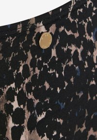 Tissu noir avec un motif à pois dans des nuances de beige et de bleu, avec des détails de bouton doré marqués "Mint Velvet."