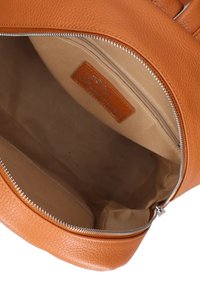 Open tan leren handtas met een beige stoffen interieur en een ritszakje binnenin.
