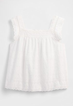 Vit ärmlös topp med insamlad design, vågiga kanter och blommiga hålmönster med fina detaljer längs banden.