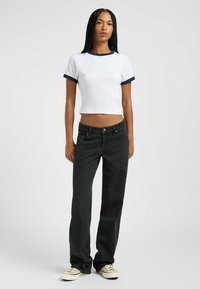 Hvid cropped t-shirt med marineblå ribkant, parret med sort lige ben jeans og beige sko. Glat stofstruktur, afslappet pasform.
