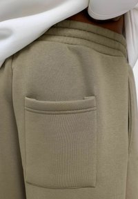Khaki joggers van een zachte katoenmix, met een gestikte zak aan de zijkant en een elastische tailleband voor comfort. Glad textuur.