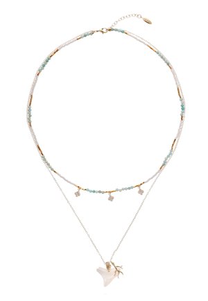 Collier multi-couches avec chaînes en argent, perles aqua, accents dorés et pendentif en coquillage blanc orné d'un détail en forme de branche décorative.