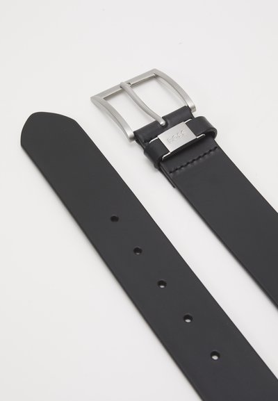 Cinturón de cuero negro con una hebilla metálica de plata pulida. Presenta una textura suave y múltiples agujeros para ajustes. Detalle del logo visible en la hebilla.