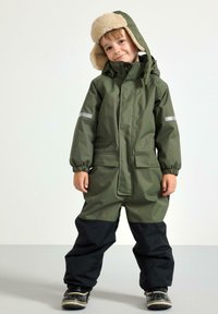 Tutina impermeabile verde con parte inferiore nera, dettagli riflettenti e cappuccio foderato in pelliccia sintetica color sabbia. Presenta polsini elasticizzati e due tasche frontali.