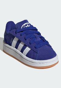 Basket bleue en suede avec un design à trois rayures blanches, semelle en caoutchouc texturé blanche et logo rond sur la languette. Dispose de lacets robustes.