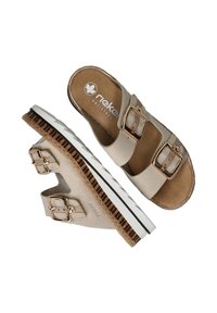 Beige sandalen met dubbele gouden gespen, een kurkachtige middenzool en een witte rubberen buitenzool. Het interieur heeft het "rieker antistress" merklabel.