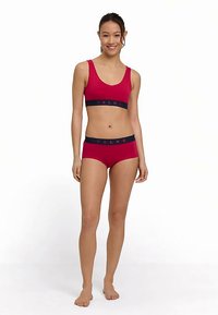 Rode sportbeha van FALKE met bijpassende slip en een marineblauwe tailleband. De stof is glad en rekbaar, met logo-accenten op de tailleband.
