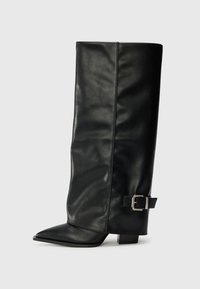 Bottes noires en cuir longueur cheville avec un bout pointu, texture lisse et une accent en boucle argentée sur le côté. Talon carré épais.