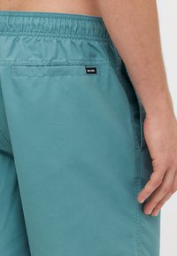 Tamsiai mėlyni maudymosi šortai su elastinga juosta, užpakaline kišene ir mažuoju juodu "Rip Curl" logotipu. Lygi medžiagos tekstūra ir kasdienis fasonas.