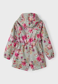 Blommig regnjacka i ljusgrått. Har rosa och lila blommor, elastisk midja och huva. Materialet ser slätt och lätt ut.