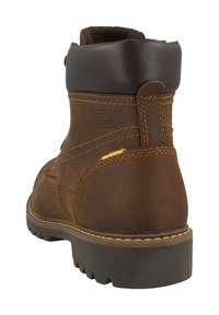 Bruine leren enkellaars met een gevoerde kraag, contrasterende stiksels en een geruite rubberen zool met opvallende noppen voor grip.