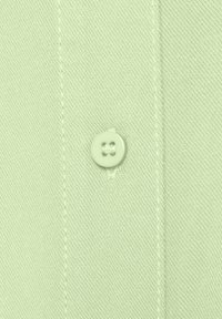 Light green buttoned shirt fabric close-up, featuring a smooth texture, single button, and visible stitching details.