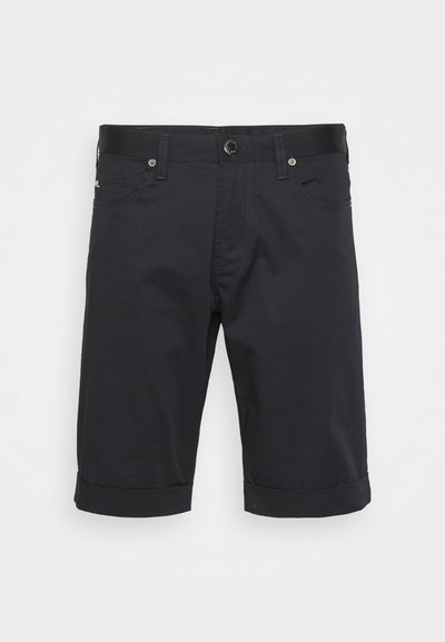 Melnas šortas, kas izgatavoti no viegla auduma, ar salocītu apakšmalu, jostu cilpiņām un priekšējām kabatām ar pogu aizdari.