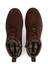 Stivali alla caviglia in suede marrone con una finitura testurizzata, dotati di fodera in tessuto verde e un interno a motivo plaid. Sei asole metalliche per i lacci.