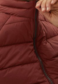 Bordeauxrote gesteppte Weste mit hohem Kragen und einem schwarzen Reißverschluss an der Vorderseite. Glatte Textur mit gepolsterten, isolierten Abschnitten.