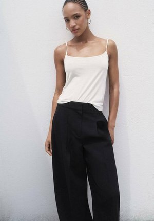 White camisole with thin straps, paired with high-waisted, wide-leg black trousers. Smooth fabric and tailored fit, minimalistic design.
