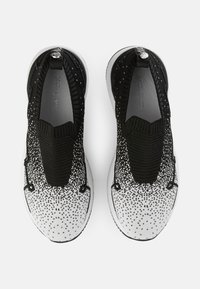 Schwarz-weiße Sneakers mit einem Verlaufsmuster, gestricktem Obermaterial, elastischem Kragen und einer strukturierten Sohle mit einem Diamantakzent.