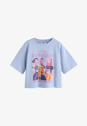 Hellblaues Baumwoll-Bauchfreies Top mit einem lebendigen Grafikdruck von drei Charakteren mit verschiedenen Frisuren und Outfits, beschriftet mit "ZOEY, RUMI, MIRA".