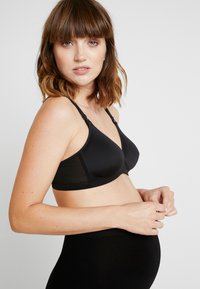 Black maternity bra with a seamless design, adjustable straps, and a smooth texture. Features a triangular cup shape and no padding.