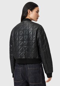 Gequilte zwarte leren bomberjack met ribbelmanchetten en onderrand. Heeft een cropped ontwerp en een geometrisch stikpatroon.