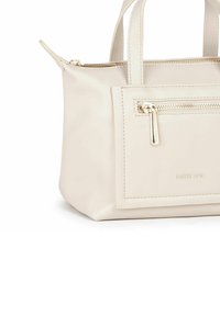 Lys beige kunstlæder håndtaske med to korte håndtag, en lomme med lynlås foran og præget logodetalje. Glat overflade og kompakt form.