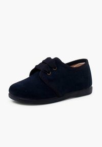 Námořnické modré papuče vyrobené z měkké, strukturované látky. Zaoblená špička, elastický pásek přes nárt a nízká, plochá gumová podrážka.