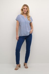 Top de rayas azul y blanco de manga corta con escote en V, combinado con jeans skinny azul oscuro y sandalias de tacón cuadrado marrón claro.