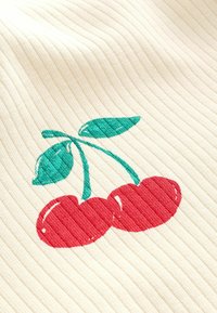 Baumwollstoff mit einer gerippten Textur, der ein rotes Kirschdesign mit grünen Blättern auf einem cremefarbenen Hintergrund zeigt.