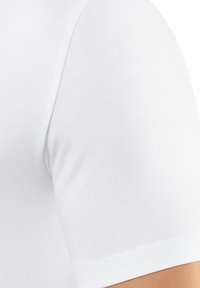 T-shirt bianco in cotone con collo a giro e maniche corte, con una texture liscia e leggera e senza disegni o accessori visibili.