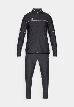 Zwart sporttrainingspak met ritsjack en broek, met witte accenten, gemaakt van een gladde, lichte stof. Logo op de borst en op het been.