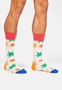 Mehrfarbige Socken mit einem pinken Bündchen, die grüne und orangefarbene Sternmuster auf weißem Hintergrund und blaue Zehenakzente aufweisen.