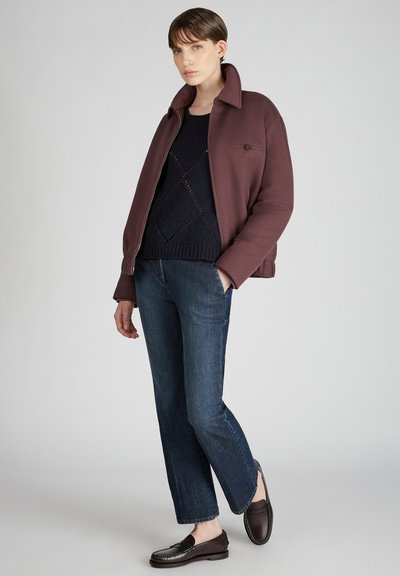 Burgunderfarbener Blazer mit Reißverschluss und Kragen, navyblauer Strickpullover, dunkelblaue Jeans und braune Lederloafers. Einfaches, strukturiertes Design überall.