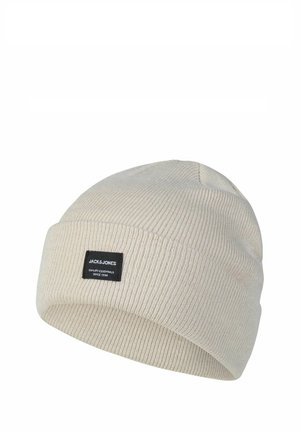Beige geribbelde gebreide muts met omgeslagen rand en een zwart rechthoekig label met de tekst "JACK & JONES QUALITY ESSENTIALS SINCE 1990".