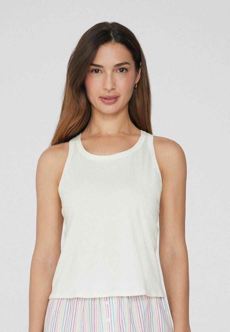 Top de tirantes de crema clara con escote redondo y tirantes anchos. Fabricado con un tejido suave y un ajuste relajado, ligeramente holgado.