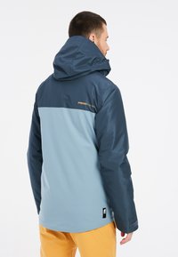 Gevoerd jack met een bicolor ontwerp; marineblauw bovenste gedeelte en lichtblauw ondergedeelte. Bevat een gestructureerd oppervlak en logo-detail.