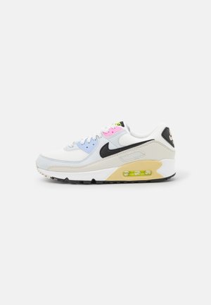 Baskets Nike Air Max blanches avec le logo swoosh noir, accents bleu pastel et rose, coussin d’air jaune visible et semelle extérieure noire, vue de profil.