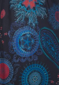 Mörkt tyg med intrikata blå och röda blommönster och cirkelmönster, med detaljerad linjearbete och varierande former genom hela.