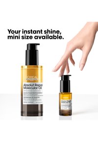 Zwei Größen von L'Oréal Absolut Repair Molecular Oil-Flaschen, eine Hand greift nach der kleineren Flasche. Im Text steht, dass eine Mini-Größe verfügbar ist.