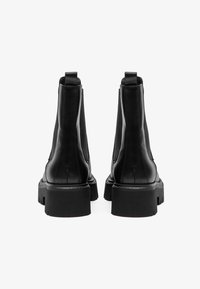 Black leather ankle boots with a smooth texture, round toe, and a chunky rubber sole. Featuring elastic side panels and pull tabs.