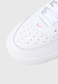 Valge tennisejalats perforatsiooniga varbaosas, sile nahk, roosa Nike logo ja heleroheline detail talla serval.