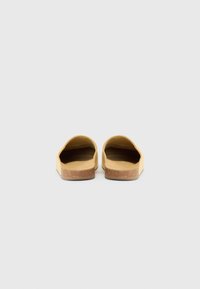 Yellow slip-on shoes with a flat sole, featuring a textured cork base and a smooth upper. Open back and rounded toe design.