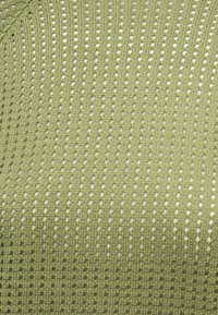 Φυστικί πλεκτό ύφασμα με κάθετες σειρές μικρών οπών που δημιουργούν μια διαπνέουσα, διακοσμητική υφή.