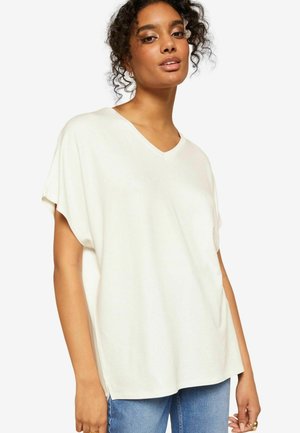 T-shirt bianco a maniche corte con scollatura a V, dalla vestibilità comoda, realizzato in tessuto morbido con una texture liscia. Presenta delle aperture laterali per un maggiore comfort.